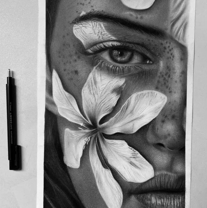 Realistic black-and-white charcoal portrait of a woman's face partially covered by a large flower, featuring a detailed eye, freckles, and smooth shading that showcases professional pencil artistry.